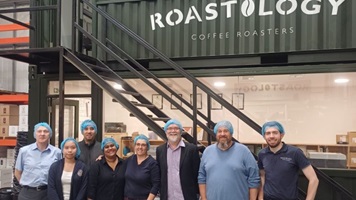 People standing under a Cafeology sign