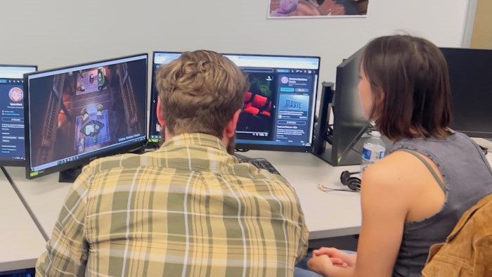 Students looking at a computer screen showcasing a computer game