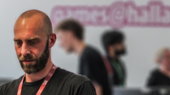 Man standing in front of the games@hallam logo with people behind