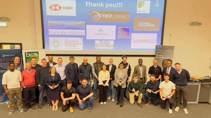 Team picture of individuals in front of a large projection
