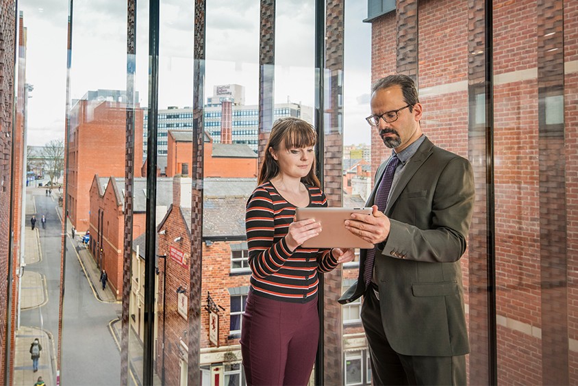 Two people standing reading a document