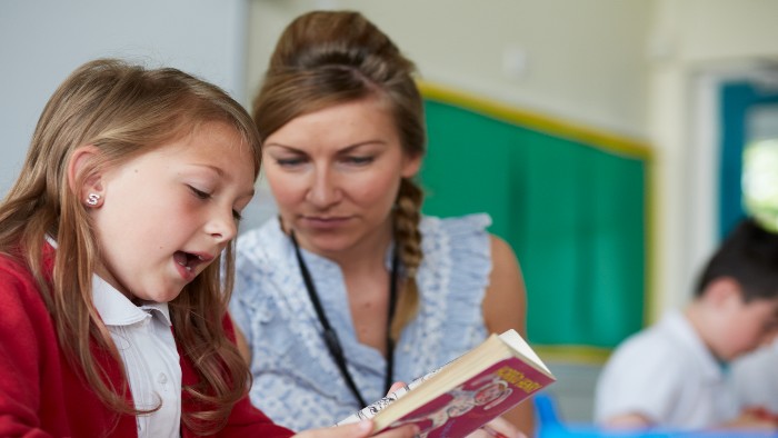 A teacher and pupil reading a story book