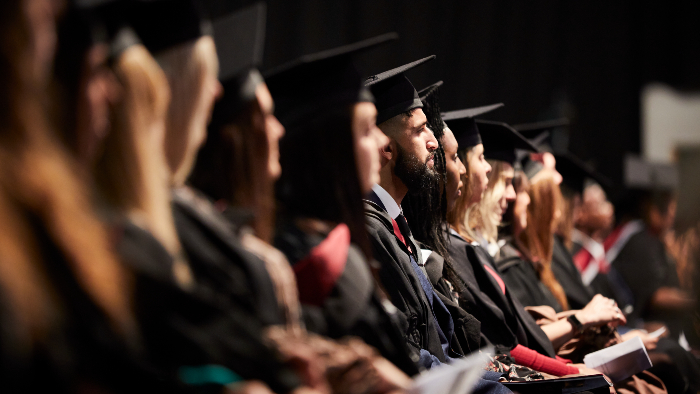 Students in the audience wearing caps and gowns at a Sheffield Hallam graduation ceremony 