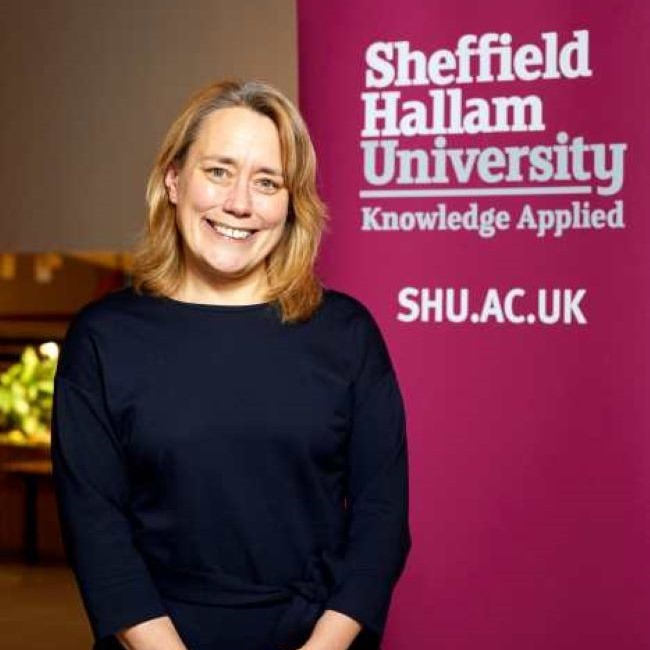 Image shows Professor Liz Mossop, Vice-Chancellor of Sheffield Hallam University, standing in front of a banner stand that says "Sheffield Hallam University, Knowledge Applied, Shu.ac.uk"