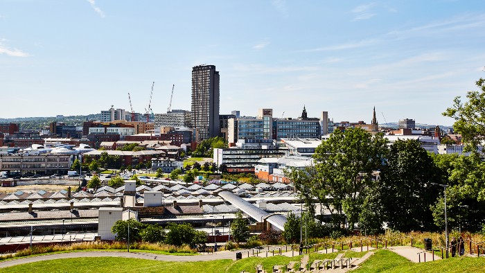 A landscape view of Sheffield with a blue sky and lots of green trees and grass