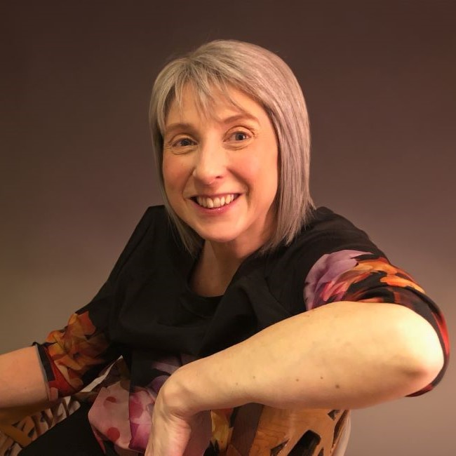 Image shows professor Aimee Aubeeluck. She is resting an elbow on a chair and smiling at the camera.