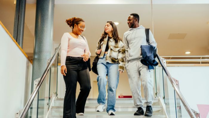 Three students walking down the stairs on campus