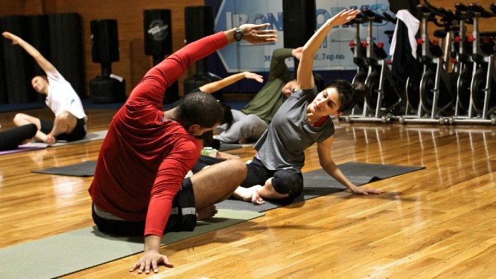 Two people sat stretching in a gym class