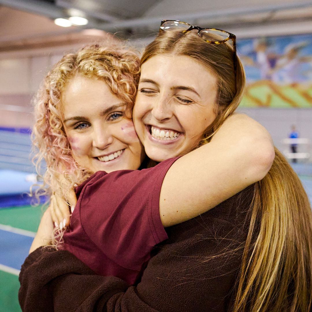 two students hugging at a sporting event