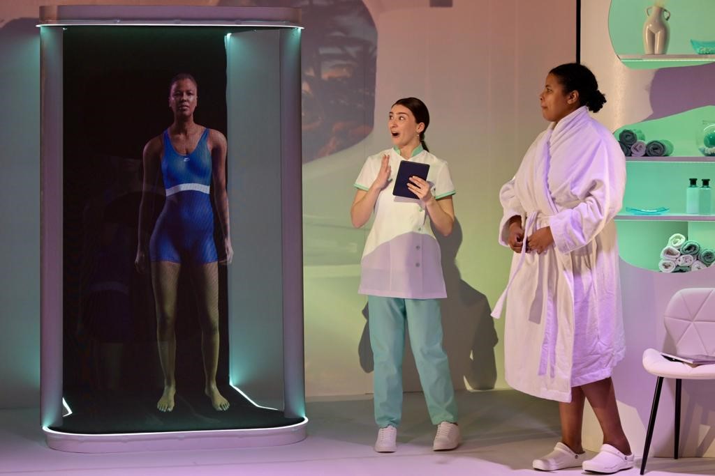 Still from the 5 Years theatre performance. It sees two actors looking at the animated body of the leading actor who has wished to have the perfect body. 