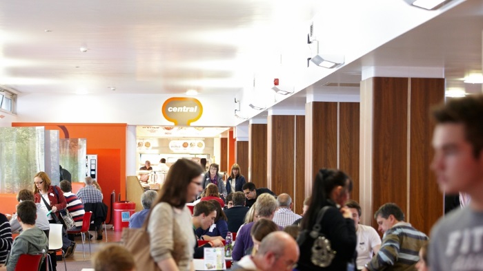 People seated and standing, eating and drinking in Chef Hallam catering outlet
