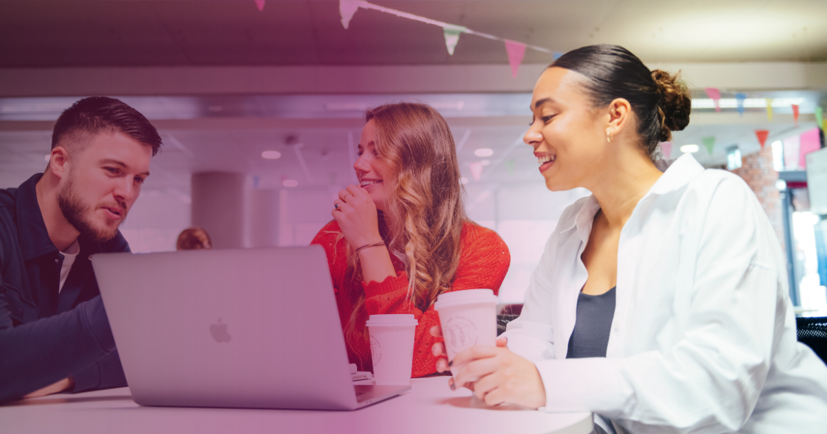 Three people meeting around a laptop, with drinks in hand