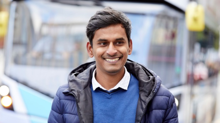 Man smiling with a bus in the background