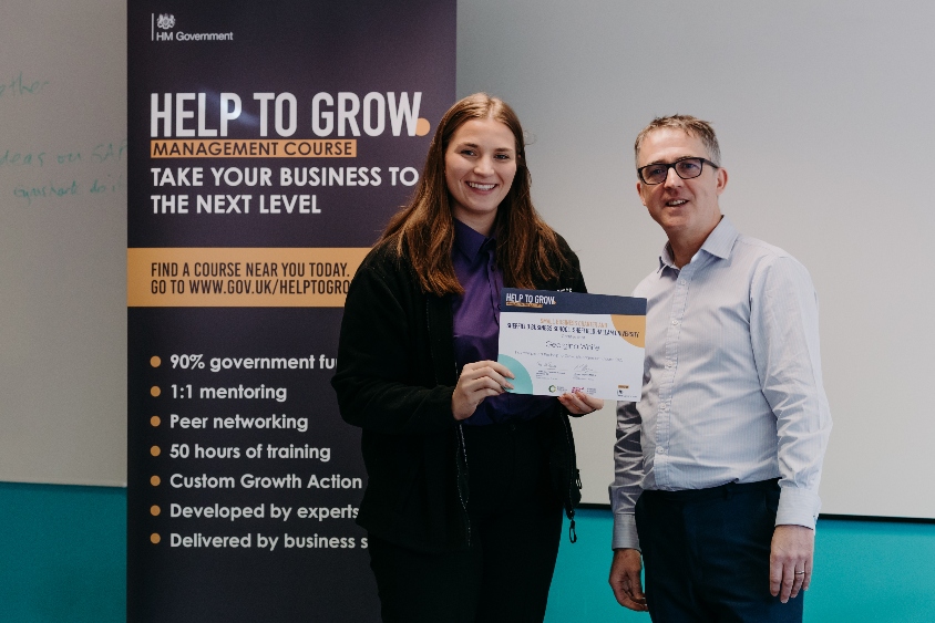 Image of Georgina White standing before a Help to Grow banner accepting a certificate
