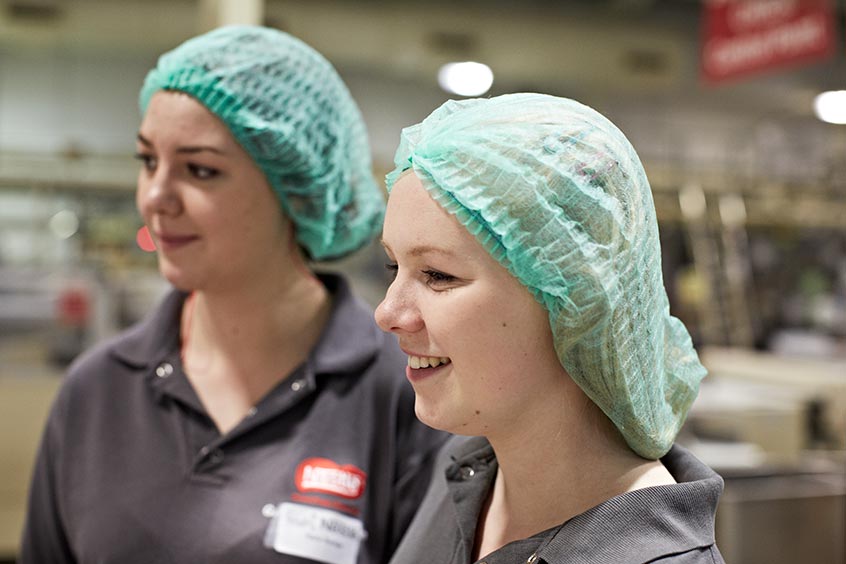 Two women wearing head nets in a factory