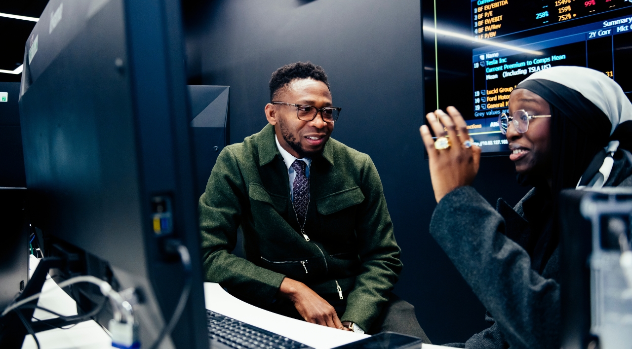 Accounting student sat at computer talking to an academic.