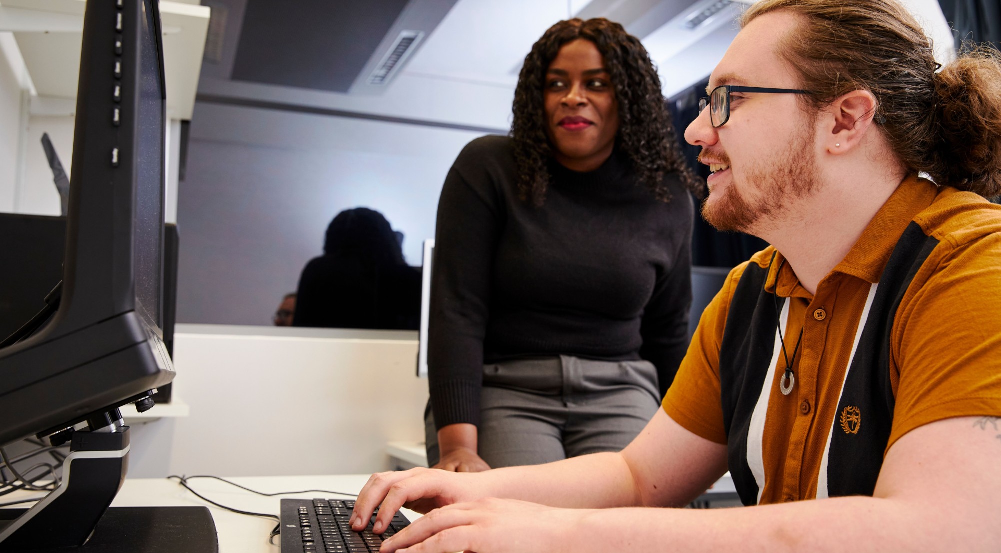 Student with PC in lab with an observation screen behind them