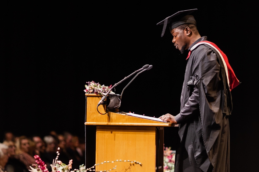 Graduate standing at the podium talking to audience