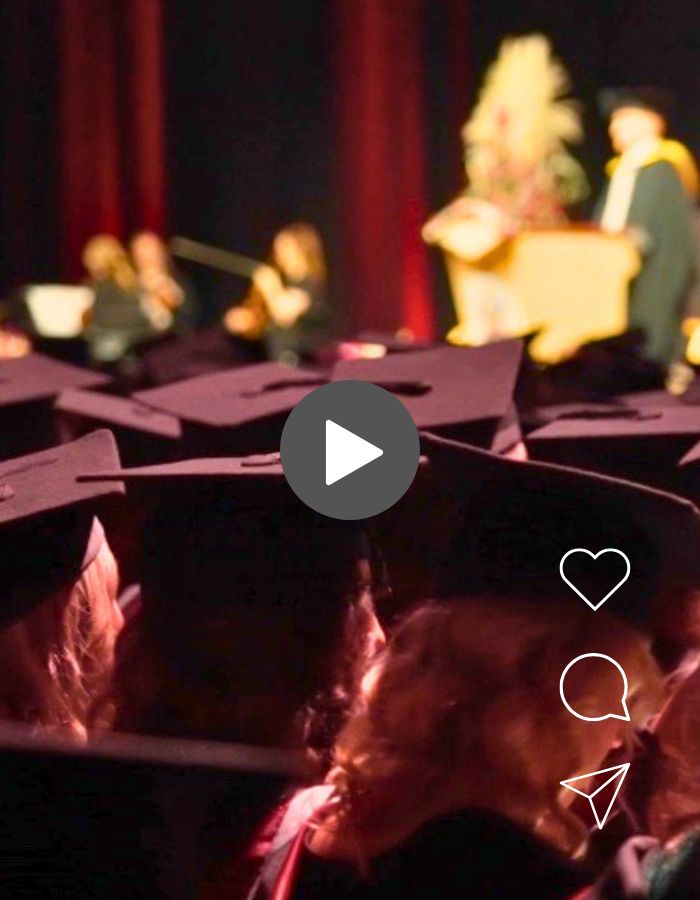 Graduates wearing graduation caps at a graduation ceremony with a stage in the background