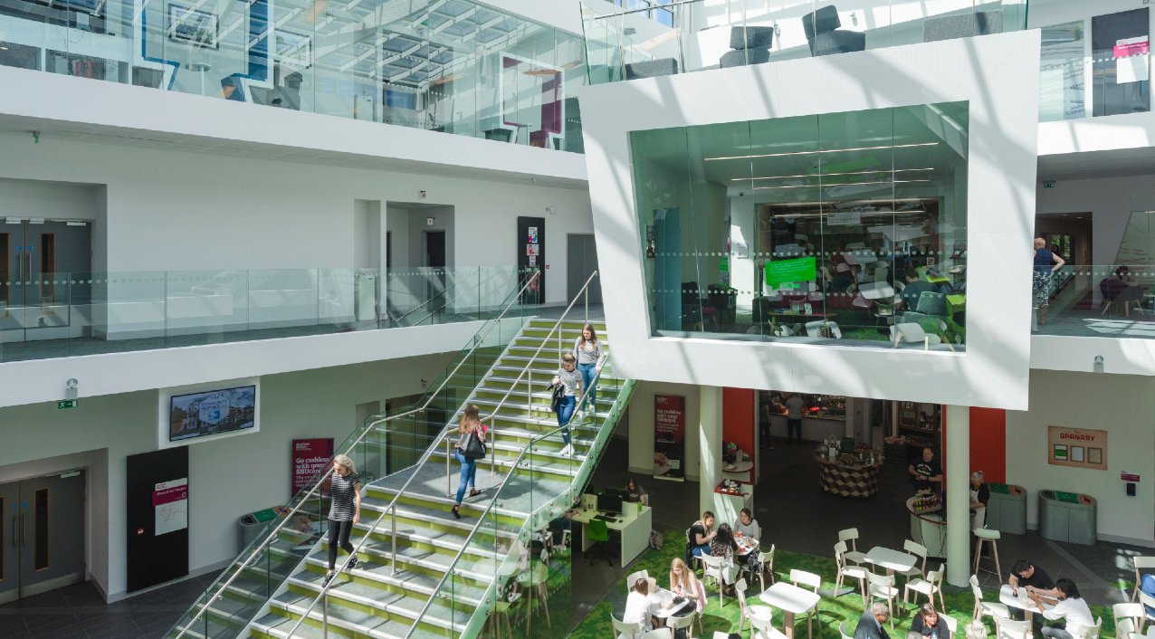 Students and staff sat at tables eating and drinking in the Heart of the Campus atrium
