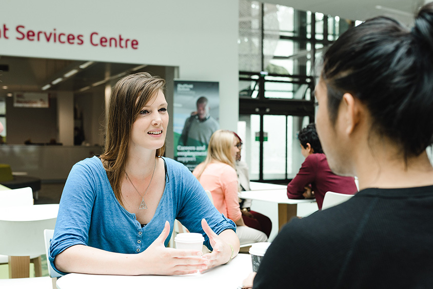 Two students at a table in conversation
