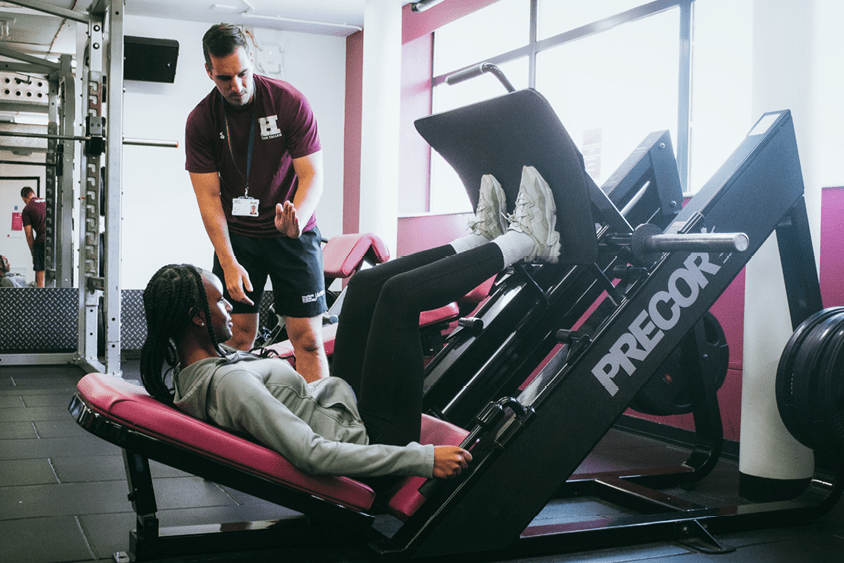 Man training a women on leg press machine 