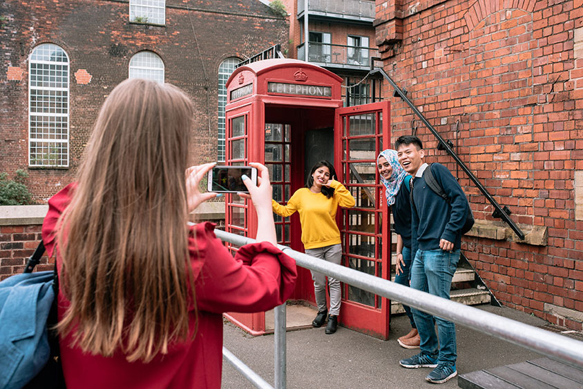 A group of students taking a photo of themselves by a telephone box