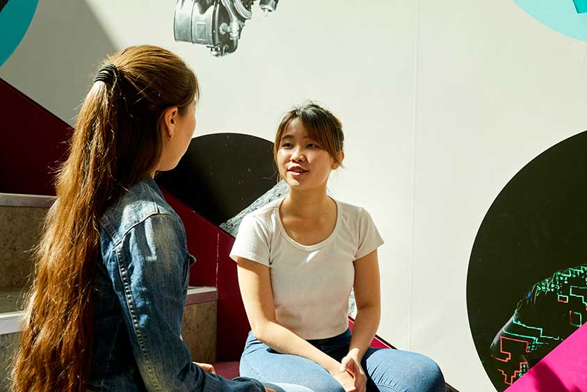 Two students talking in a campus building