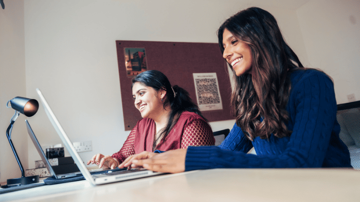 Two students on laptops in a room
