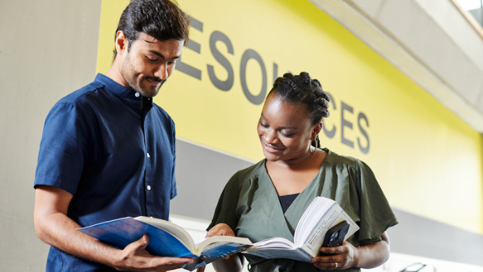 Male and female student looking at books