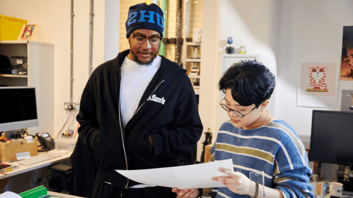 Two students surrounded by art and design equipment