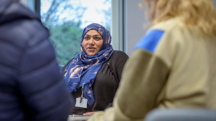 A woman in a hijab engages in conversation with two individuals, fostering a dialogue in a social setting.
