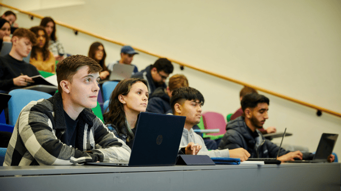 Students in a lecture theatre, with laptops open in front of them