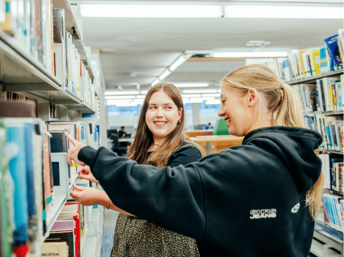 Two students browsing library shelves