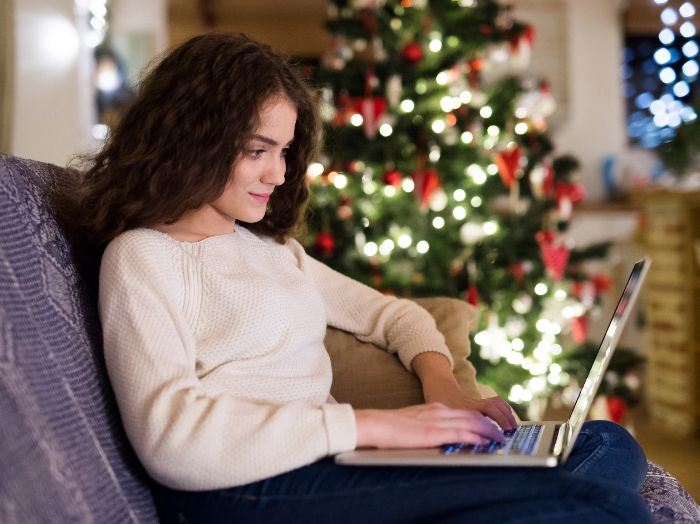 student with laptop with festive tree in the background