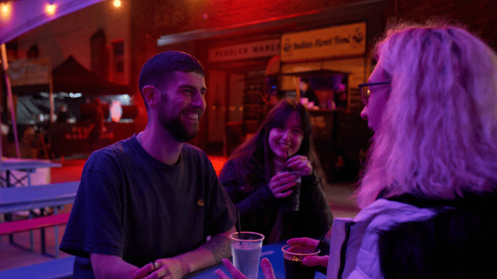 Group of three students sat at a table, drinking