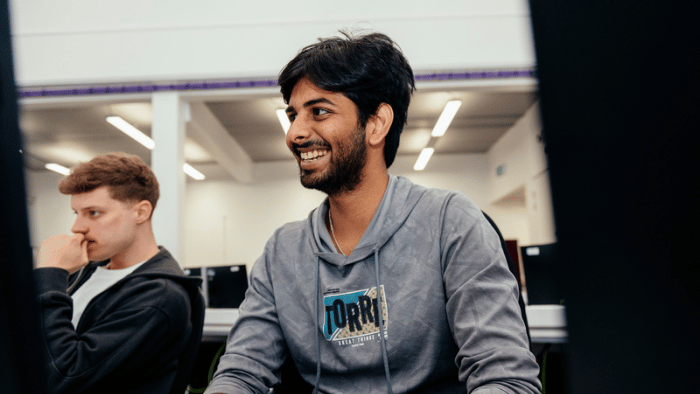 Male student smiling facing computer screen