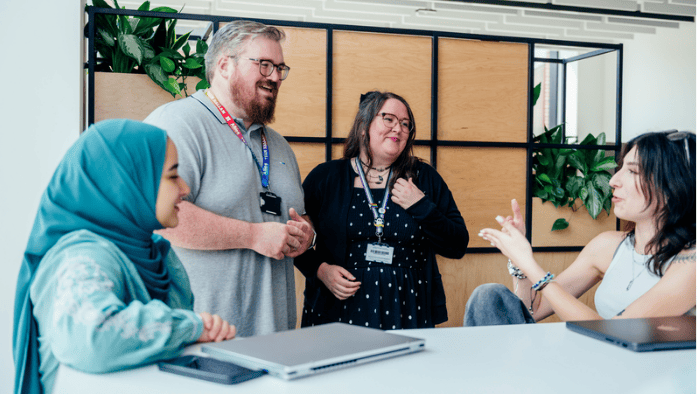 Two students sat at a table, speaking with two Hallam staff members