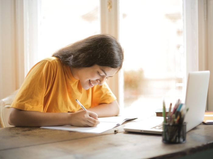 A student wearing yellow sitting at a desk