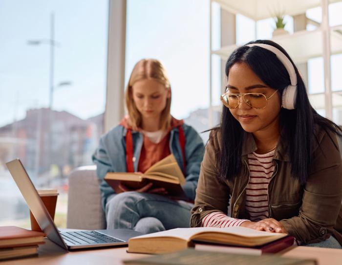 Two students work quietly alongside each other in a library.