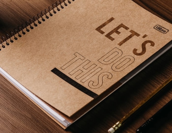 A notebook with 'Let's do this' on the cover in bold font.
