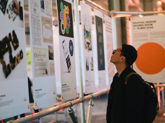 A person looking at graphic design work installed at an exhibition.