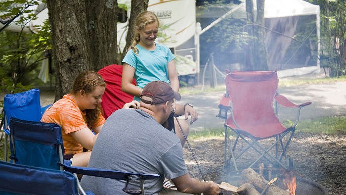 Man and two girls around a camp fire