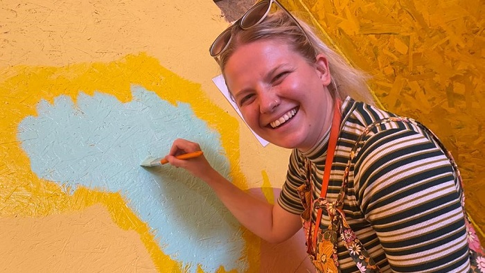 Student Chloe Gindy painting on a wall in a refugee camp in Greece