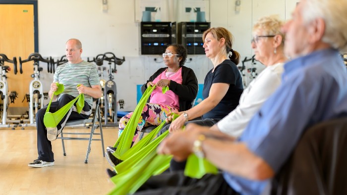 Older people taking part in an exercise class with resistance bands.