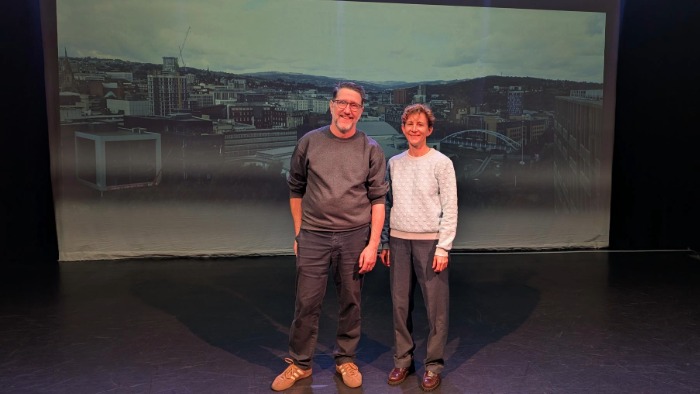 Ashley Barnes from Sheffield Hallam University and Robin Norton-Hale, CEO & Artistic Director of English Touring Opera in front of a screen showing the Sheffield skyline. 