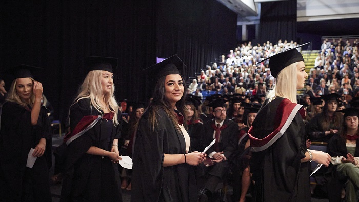 Four students on stage at a graduation ceremony at Ponds Forge 