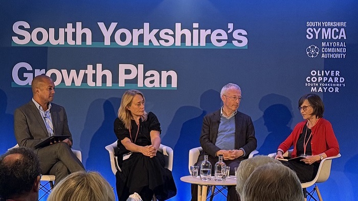 Four people sat on chairs in front of a large banner reading South Yorkshire's Growth Plan