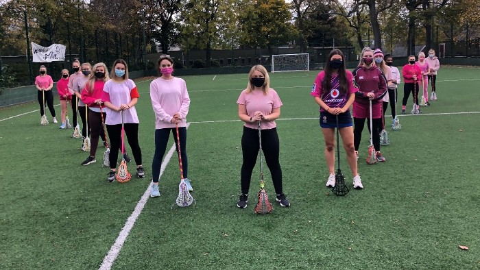 The Sheffield Hallam lacrosse team standing in a diamond formation holding their lacrosse sticks to the floor.