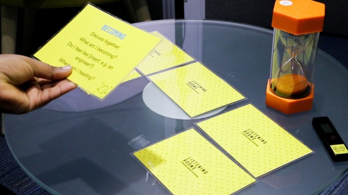 Discussion prompt cards on a table with a sand timer which was used in the Listening Rooms project.